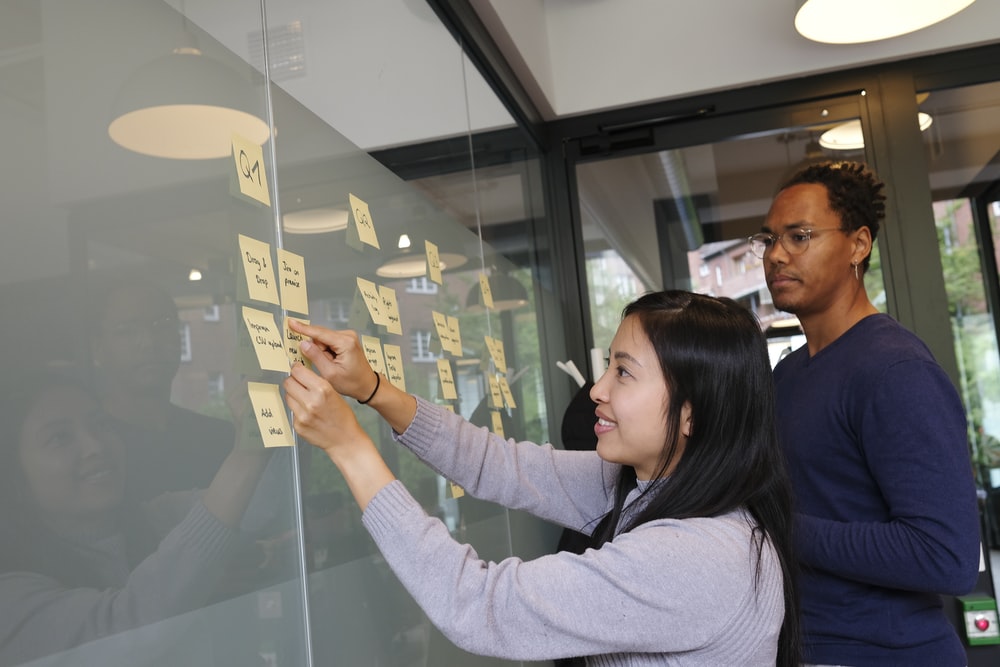 A woman and man work to use sticky notes to plan a product feature